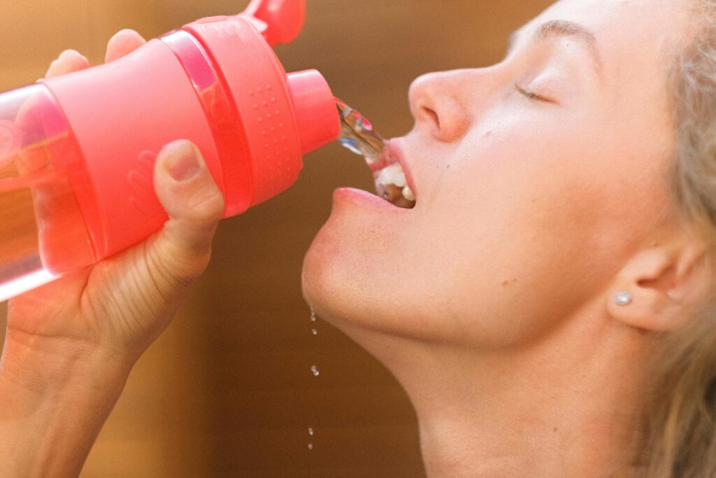 pexels-photo-5262970-5262970 Crop tired young female pouring refreshing clean water into mouth from reusable bottle after intense training